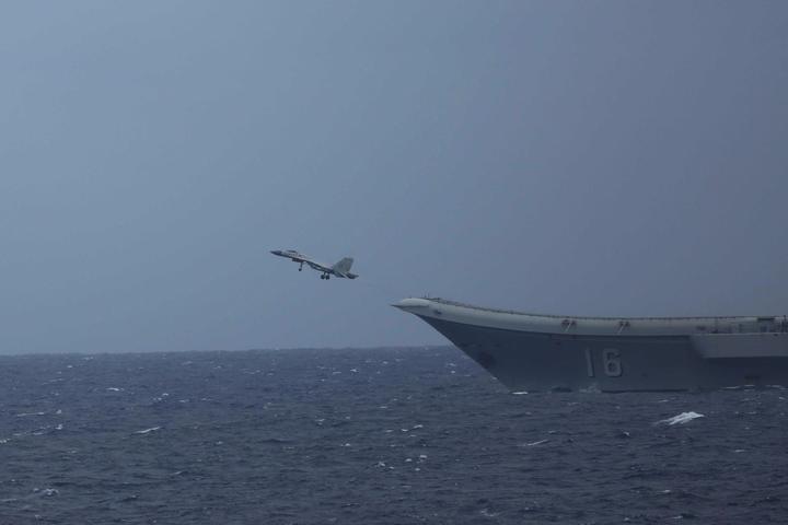 A Chinese J-15 fighter taking off beside the bow of the aircraft carrier Liaoning at sea in 2022.