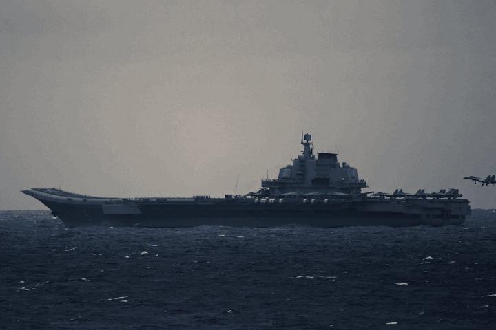 A J-15 carrier-based fighter on final approach to the aircraft carrier Liaoning, landing gear and arresting hook down, seen from astern