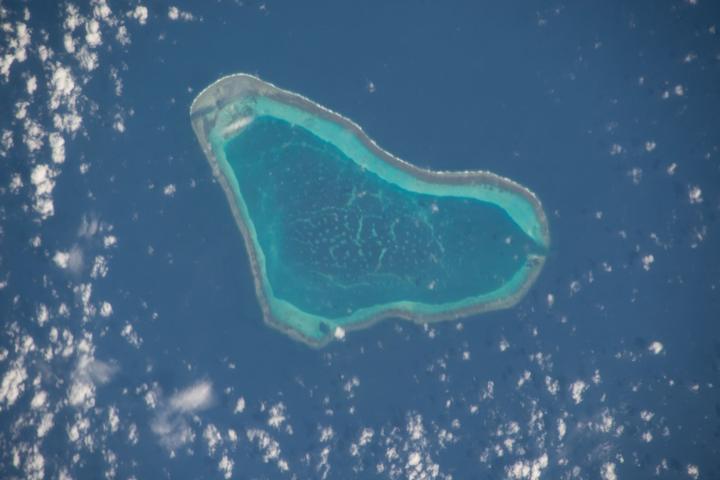 Scarborough Shoal seen as a turquoise reef within dark ocean water from the International Space Station in 2015.